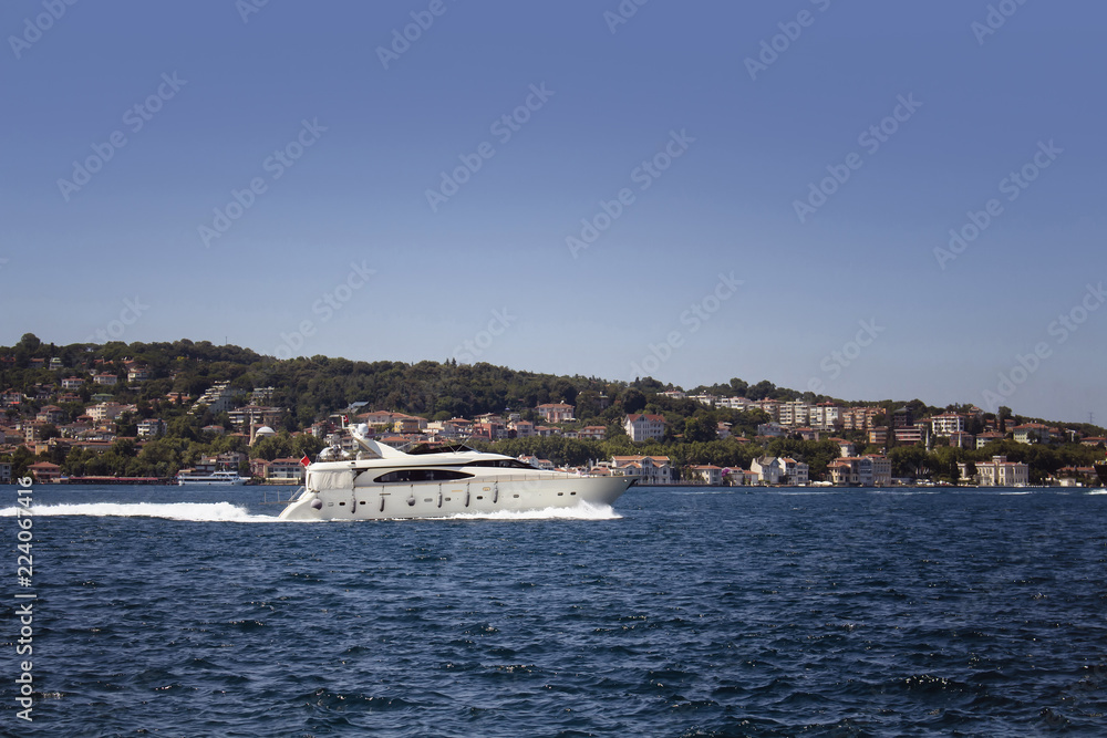 Luxury white yacht on Bosphorus in a sunny summer day in Istanbul. European side is in the background.