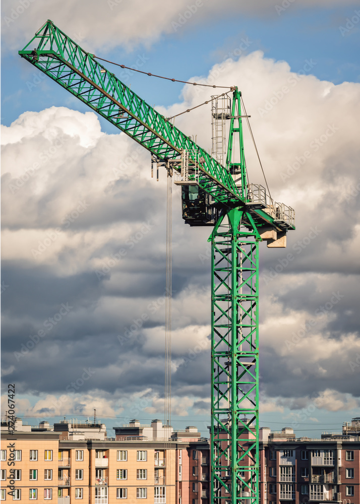 Green tower crane on a background of clouds