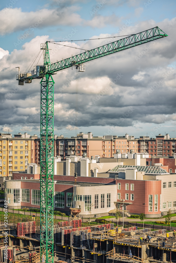 Green tower crane on a background of clouds