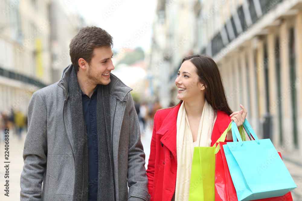 Couple of shoppers talking and walking in the street Couple of shoppers talking and walking in the street