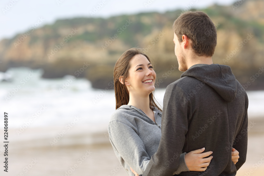 Happy couple of teens hugging and looking each other Happy couple of teens hugging and looking each other
