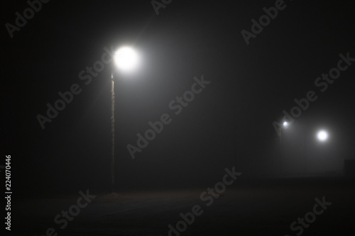 Street lights foggy misty night lamp post lanterns deserted road. Lonely street at night in the light of lanterns. foggy night parking lot