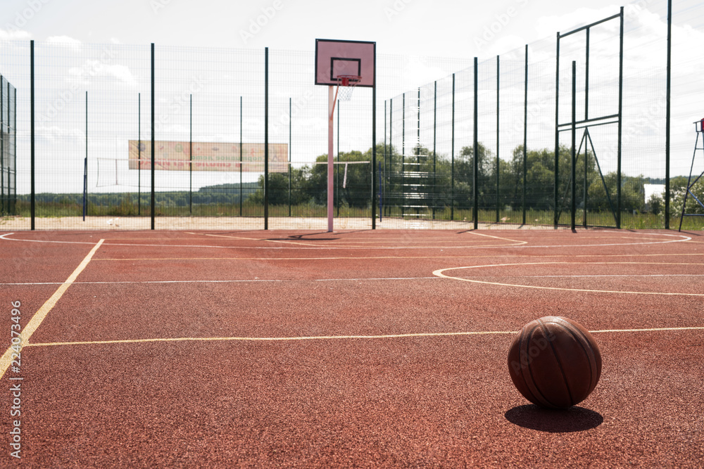 Wide angle shot of empty outdoor basketball court lit by sunlight with