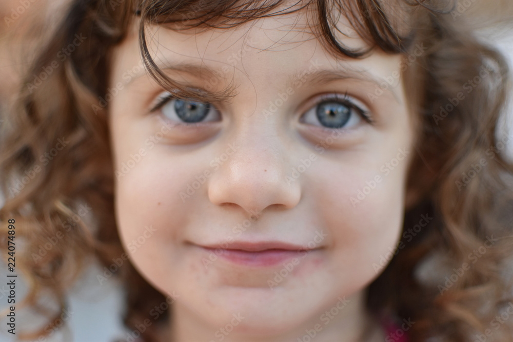 Closeup portrait of curly haired toddler with striking, huge blue eyes Closeup portrait of curly haired toddler with striking, huge blue eyes