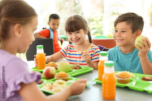 Children sitting at table and eating healthy food during break at school