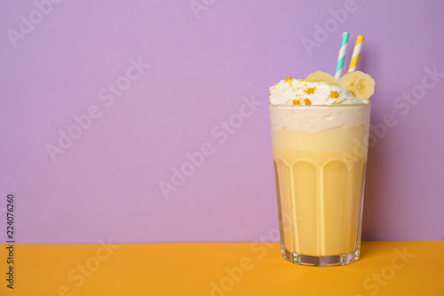 Glass of tasty milk shake and space for text on color background