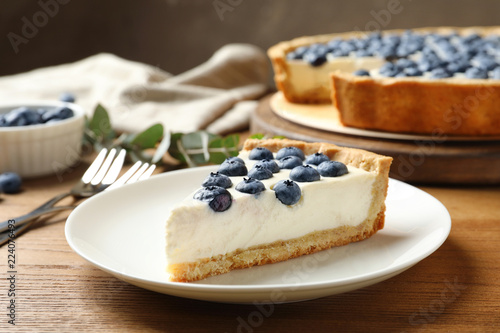Plate with tasty blueberry cake on wooden table