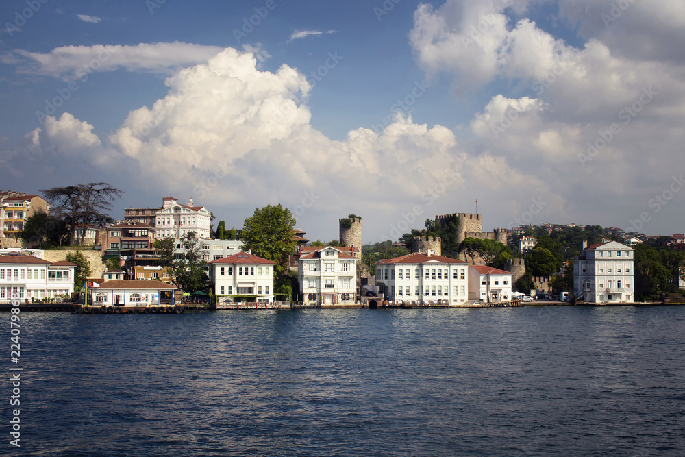 View of historical, old Turkish / Ottoman houses and a castle by Bosphorus on Asian side of Istanbul. It is a sunny / cloudy summer day.