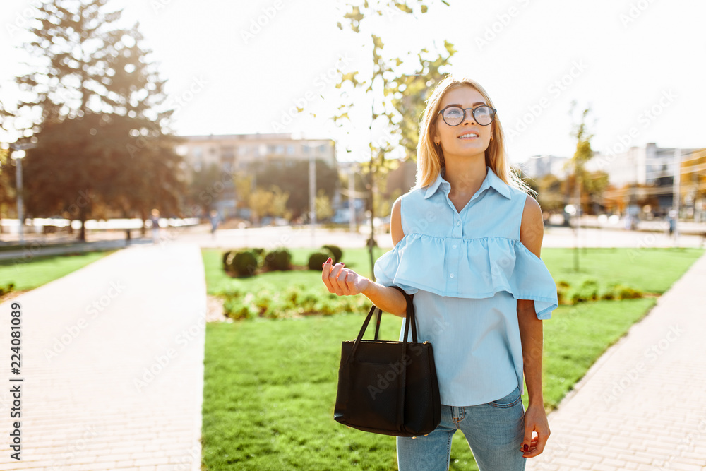 Fototapeta premium Young beautiful girl with glasses, student strolling in the Park, in a good mood