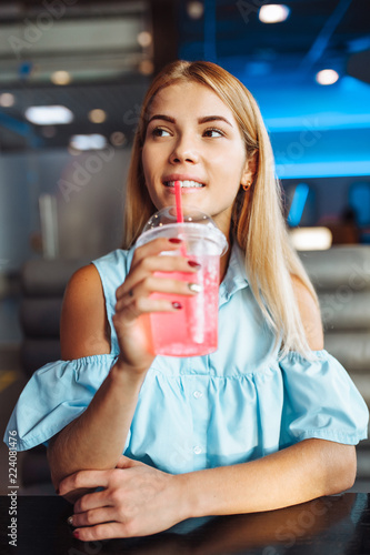 Beautiful young girl, drinking a cocktail, sitting in a cafe and waiting for someone photo
