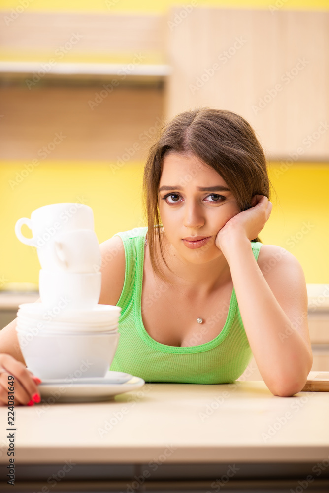 Young woman cleaning and washing dishes in kitchen Young woman cleaning and washing dishes in kitchen