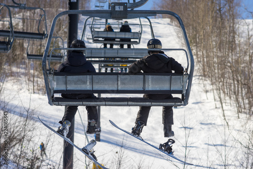 Two snowboarders ride the chairlift
