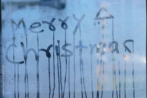 Texture of water droplets on clear window glass with Merry Christmas text