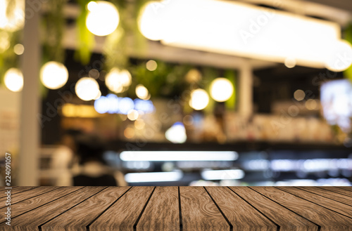 Wooden board empty table and blurred or defocus background and light bulb bokeh . Perspective brown wood table over blur in bakery shop background , this image in coffee shop and bakery shop concept