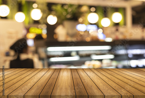 Wooden board empty table and blurred or defocus background and light bulb bokeh . Perspective brown wood table over blur in bakery shop background , this image in coffee shop and bakery shop concept