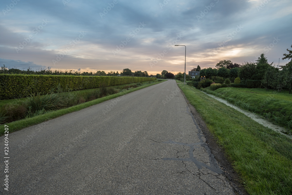 asphalt road next to a stream