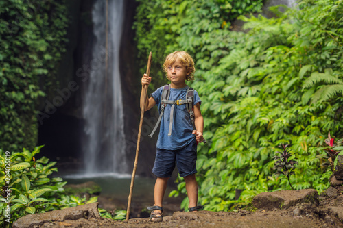 Fototapeta Boy with a trekking stick on the background of Leke Leke waterfall in Bali island Indonesia