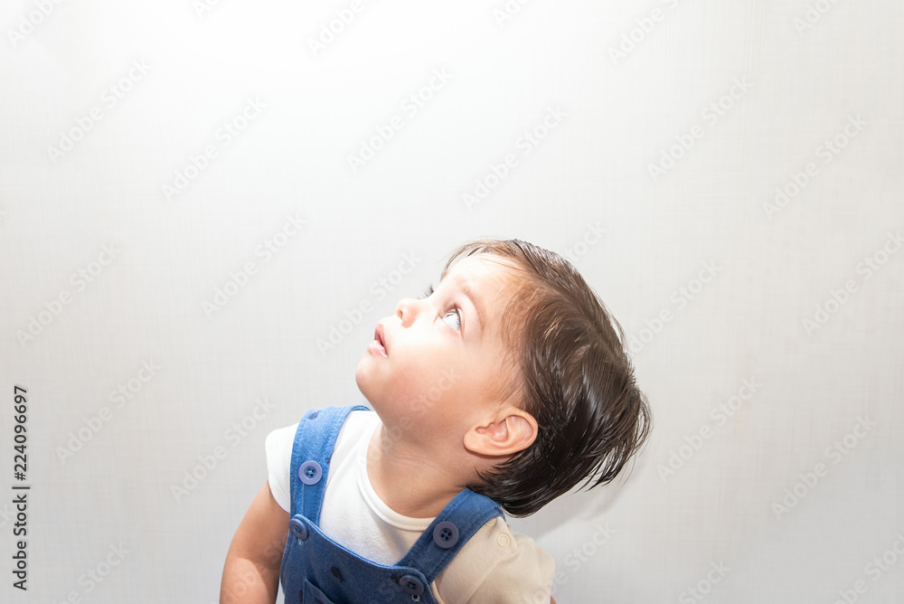 Cute baby boy toddler - with blue romper on white background - Looking at light Cute baby boy toddler - with blue romper on white background - Looking at light