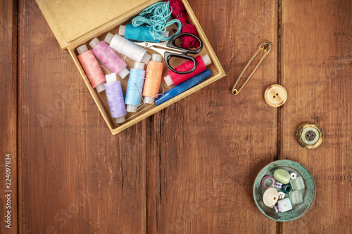 Overhead photo of sewing box with threads, needles, scissors, vintage pin, buttons, and copy space