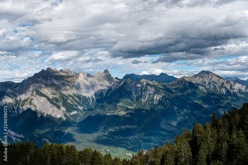mountain landscape in the Swiss Alps above Maienfeld with many peaks and forests and valleys below in early autumn 