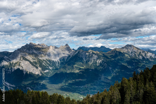 mountain landscape in the Swiss Alps above Maienfeld with many peaks and forests and valleys below in early autumn 