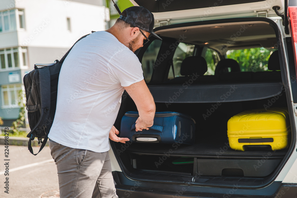 man putting bags in car trunk. ready for car travel man putting bags in car trunk. ready for car travel