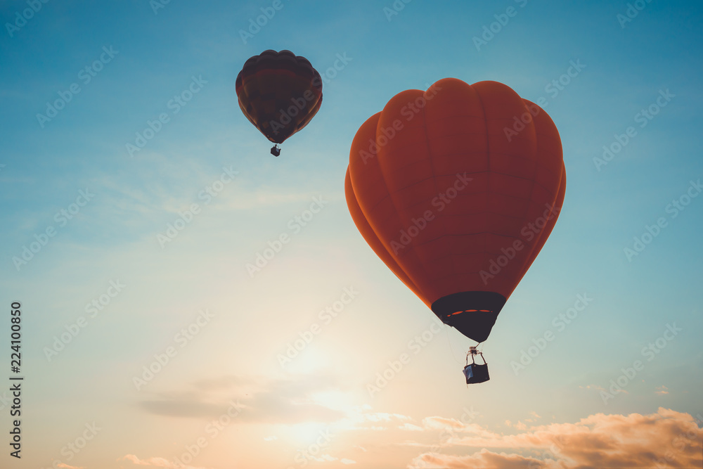 Naklejka premium Hot air balloon flying on sky at sunset. travel and air transportation concept - vintage and retro filter effect style