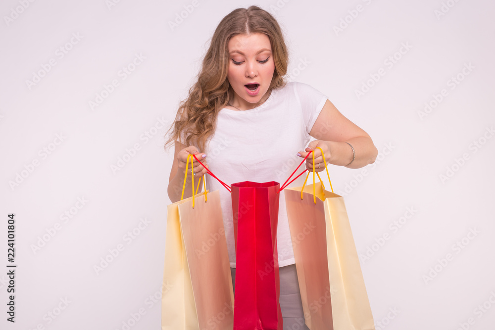 Young surprised woman look into the shopping bag on white background