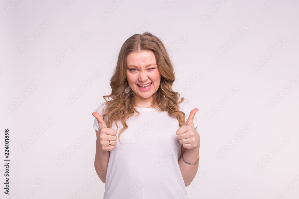 Fashion, style and gesture concept - winking pretty woman over white background showing thumbs up on white background Fashion, style and gesture concept - winking pretty woman over white background showing thumbs up on white background