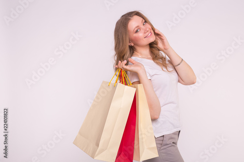 Happy beautiful young woman with shopping bags on white background with copy space