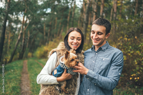 Pretty couple with little yorkshire terrier walking in the forest. © bedya