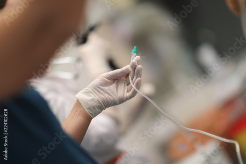 The nurse's hand with a tube for medication to the patient during surgery