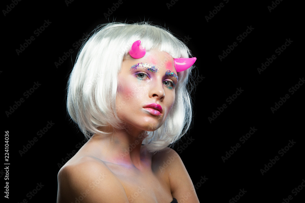 Halloween. Portrait of young beautiful girl with make-up. With white hair and pink devil horns. Isolated on black background. Halloween. Portrait of young beautiful girl with make-up. With white hair and pink devil horns. Isolated on black background.