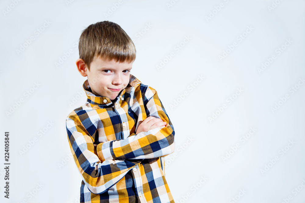 A small boy in a checked shirt on a white background folded his hands in a businesslike way. A small boy in a checked shirt on a white background folded his hands in a businesslike way.