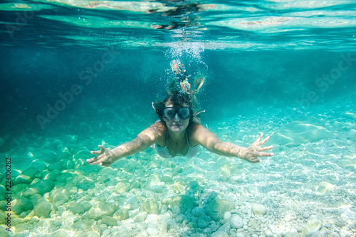 Smiling woman with mask underwater snorkeling in the clear tropical water