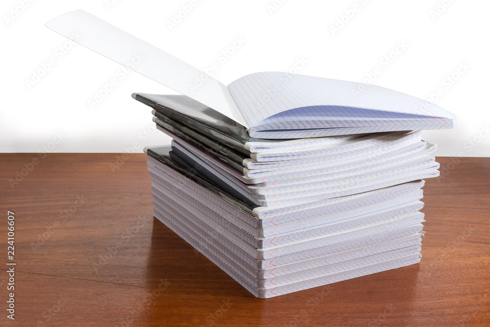 Open exercise book on stack of other exercise books Open exercise book on stack of other exercise books