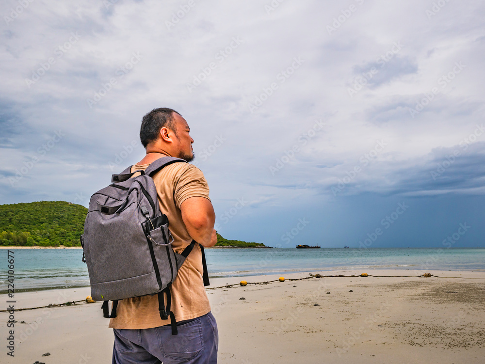 Asian fat Backpacker stand on the idyllic beach with Rainy cloud Sky in vacation time.Samae San Island thailand.Summer concept.