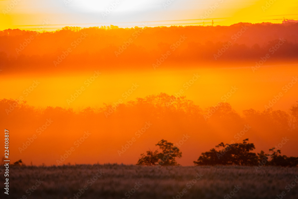 Golden and orange sunrise iluminating a hills and fields