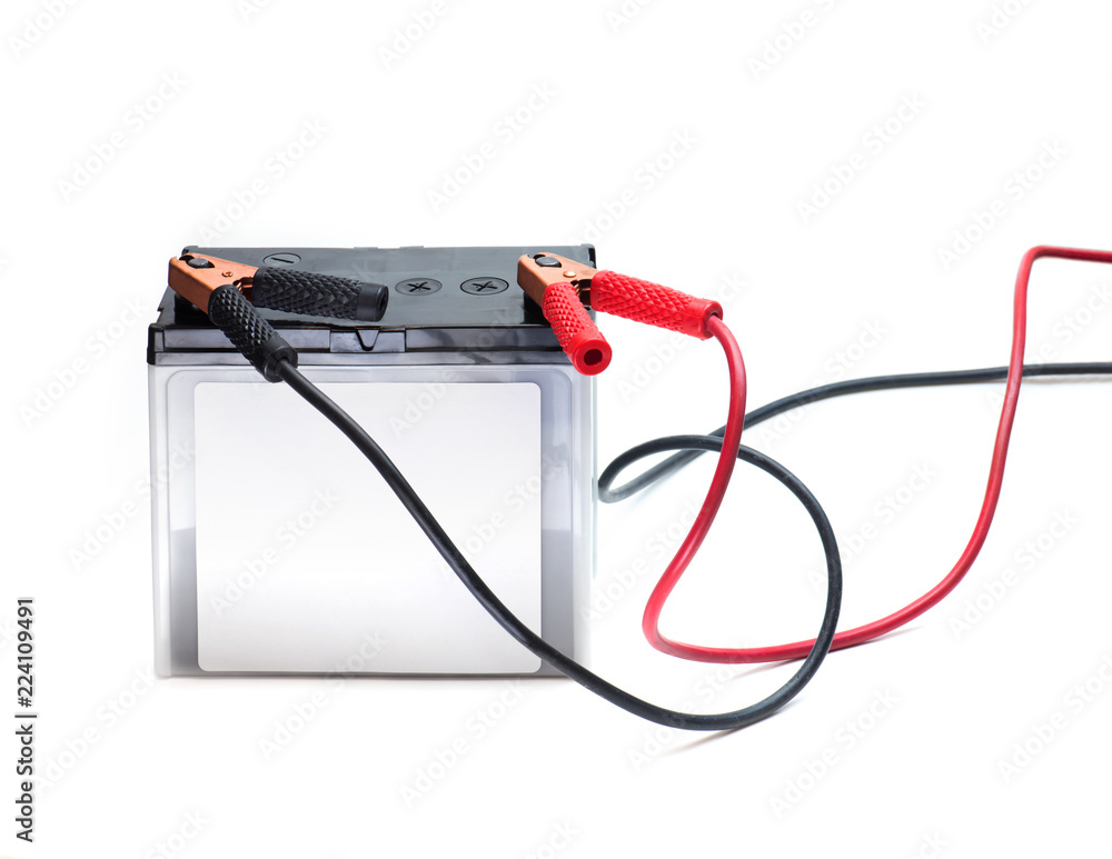 A Car battery with red and black battery Jumper or booster cables with copper clamps attached to the terminals. Automotive battery isolated on white. A Car battery with red and black battery Jumper or booster cables with copper clamps attached to the terminals. Automotive battery isolated on white.