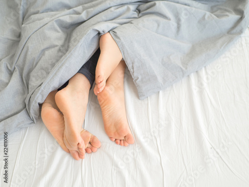 Feet of couple side by side in bed. Morning