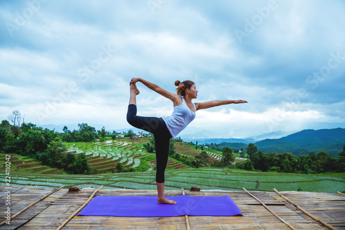 Asian woman relax in the holiday. Play if yoga. On the balcony landscape Natural Field