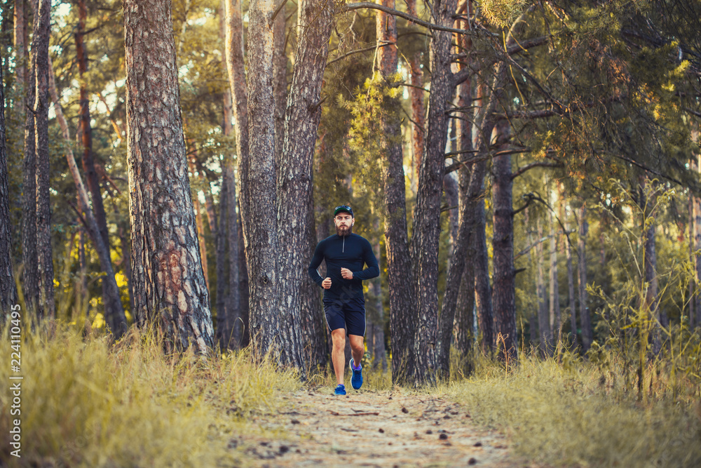 A bearded athlete runs along a picturesque forest path. healthy lifestyle concept A bearded athlete runs along a picturesque forest path. healthy lifestyle concept