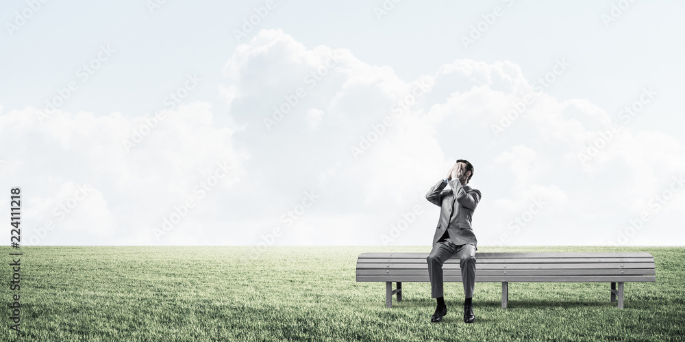 Young man in summer park on bench do not want to see anything