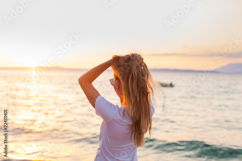 Woman facing sunrise in front of the sea