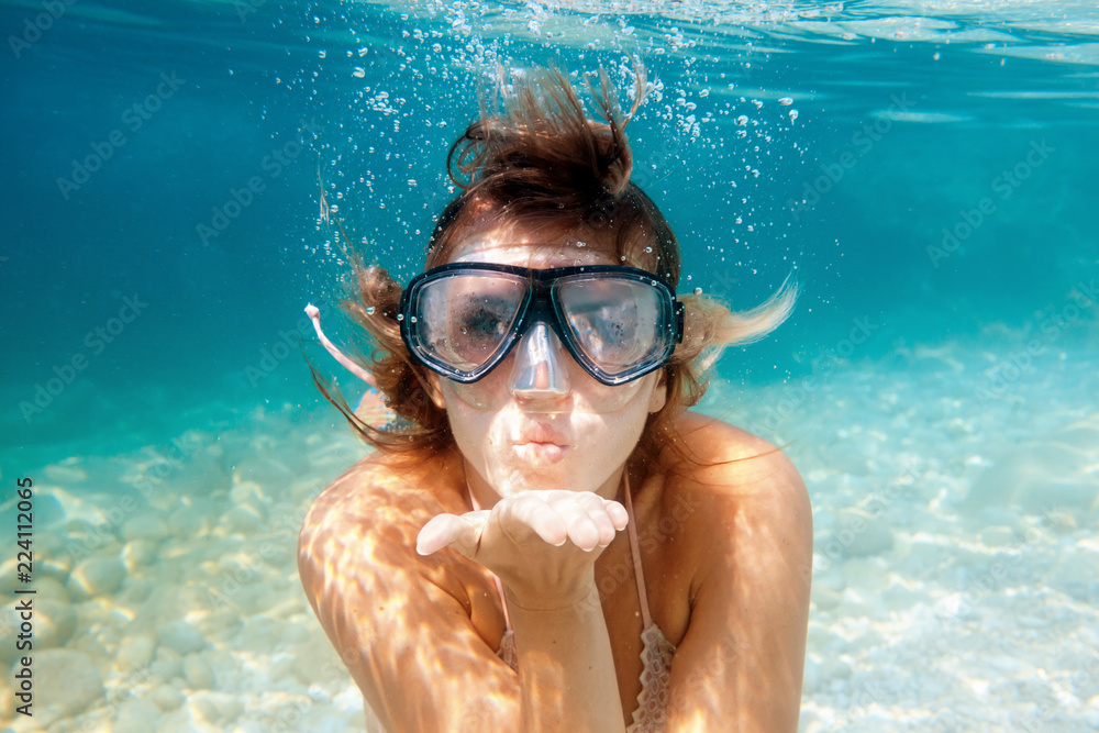 Naklejka premium Woman underwater snorkeling in the clear tropical water and blowing a kiss