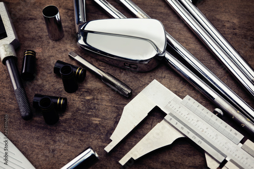 Golf club making. Golf club components on a work desk or work bench.  Focus is on black ferrule parts. Intentionally shot in grungy ,muted tone.
