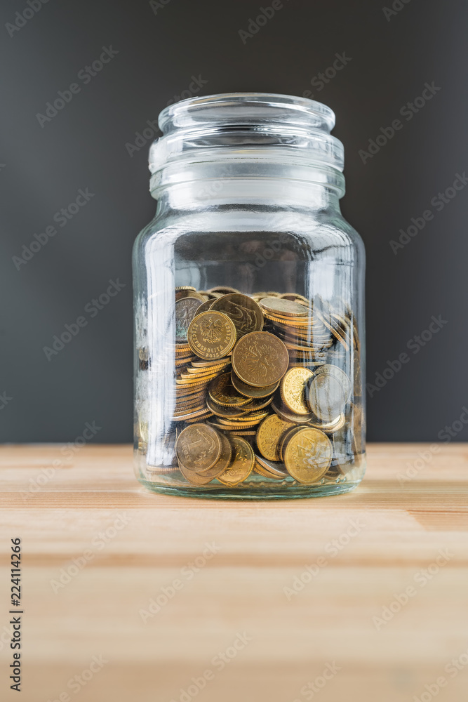 Jar with golden coins on natural wooden background. Money saving abstract concept. Jar with golden coins on natural wooden background. Money saving abstract concept.