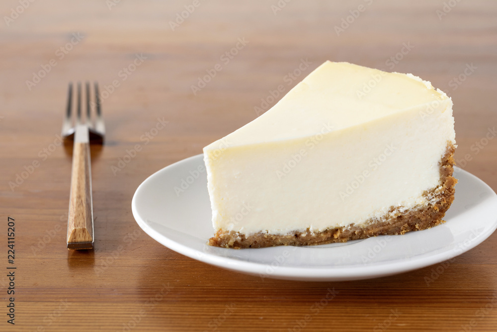 Slice of plain New York Cheesecake on wooden table. Horizontal composition Slice of plain New York Cheesecake on wooden table. Horizontal composition