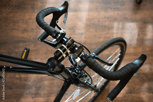 Road bike or racing type bicycle, on a wooden floor of a cycle workshop. Focus on handle , shallow depth of field.