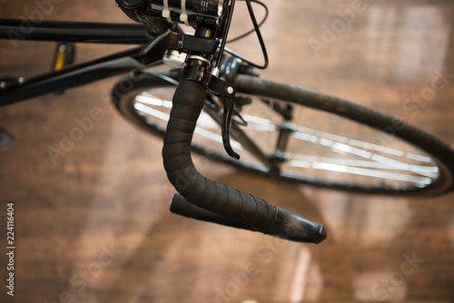 Road bike or racing type bicycle, on a wooden floor of a cycle workshop. Focus on handle grip, shallow depth of field.
